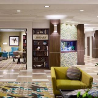 A modern lobby featuring a comfortable seating area, library section, and an illuminated aquarium.
