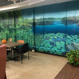 A serene office workspace featuring a vibrant nature-themed mural depicting a tranquil water scene.