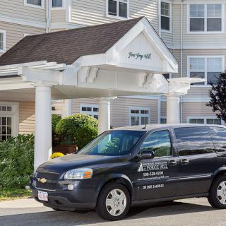 A hotel shuttle van parked in front of a building's entrance.