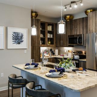 A modern kitchen with a central island, stainless steel appliances, and elegant pendant lighting.