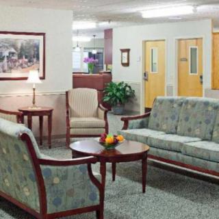 A comfortable waiting area with sofas, chairs, and a table in a well-lit lobby.
