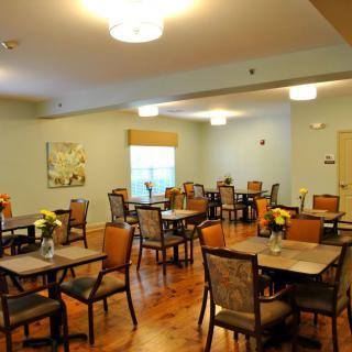 A spacious dining room with multiple tables and chairs, featuring warm lighting and elegant decor.