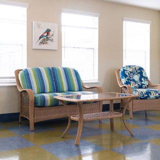 A cozy living room setup with patterned cushions on a sofa and chairs, accompanied by a glass-top table.