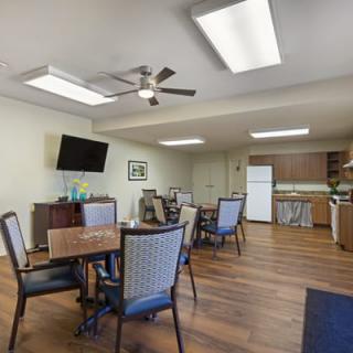 A modern dining area with tables and chairs, a television, and a kitchen setup.