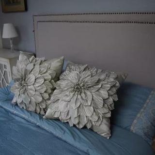 A bed with flower-designed pillows and blue bedding.
