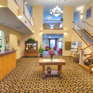 A spacious hotel lobby with a reception desk, central decorative table, and chandelier lighting.