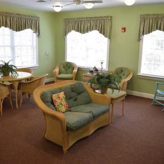 A cozy living room with green walls, comfortable seating, and abundant natural light.