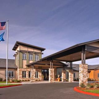 A modern building entrance with flags and a clear blue sky.
