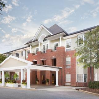 A brick hotel building with a prominent entrance and surrounding trees.