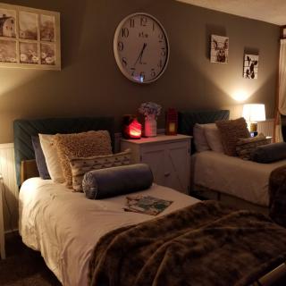 A cozy bedroom with twin beds softly lit by lamps, adorned with plush pillows and blankets.