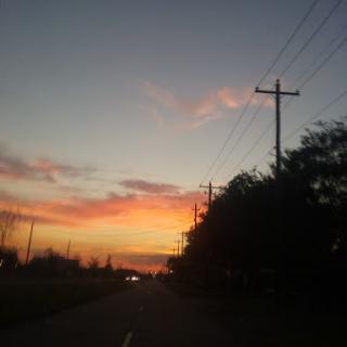 A serene sunset casting vibrant colors across the sky along an empty road.