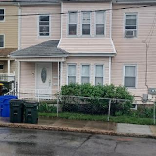 A charming pink house with a small front yard, partially obscured by rain.