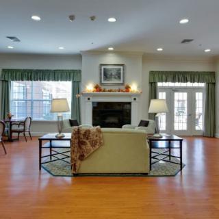 A spacious living room with a central sofa, fireplace, and large windows.