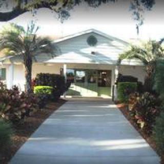 A building entrance flanked by palm trees and landscaping.