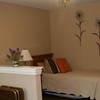 A cozy bedroom with a neatly made bed, decorative pillows, wall art, and a table lamp.