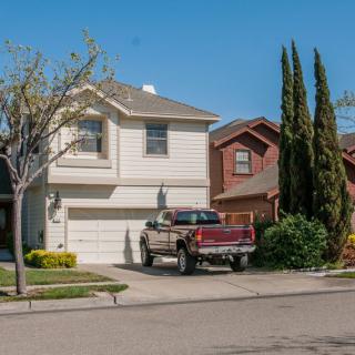 A suburban house with a truck parked in the driveway under a clear blue sky.