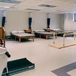 A rehabilitation room with exercise equipment and beds for physical therapy.