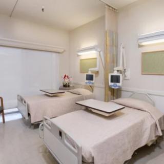 A clean and organized hospital room with two beds and medical equipment.