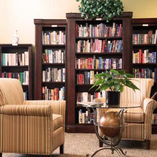 A cozy reading area with bookshelves, chairs, and a plant.