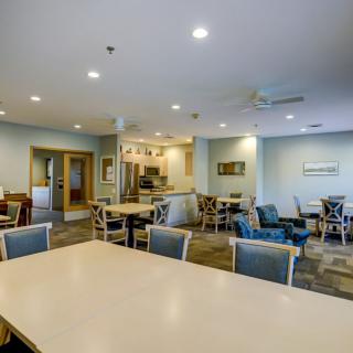 A modern dining area with multiple tables and chairs, featuring ceiling lights in a spacious interior.