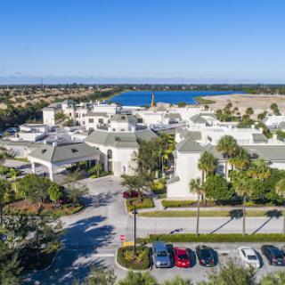 Aerial view of a luxurious waterfront resort featuring modern architecture and lush palm landscaping.