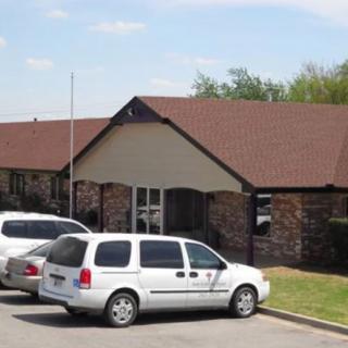 A suburban building with a parking lot and several vehicles parked in front during the daytime.