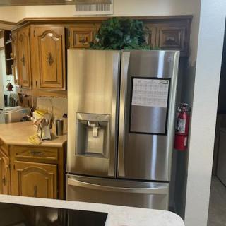A modern kitchen with a stainless steel refrigerator and wooden cabinets.