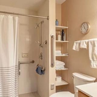 A well-organized bathroom featuring a shower with a curtain, shelves stocked with towels, and essential toiletries.