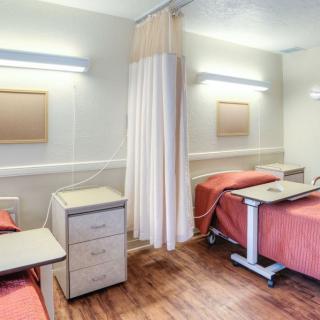 A clean and minimalist hospital room with two beds separated by a curtain.