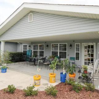 A cozy house with a spacious patio adorned with potted plants and outdoor seating.