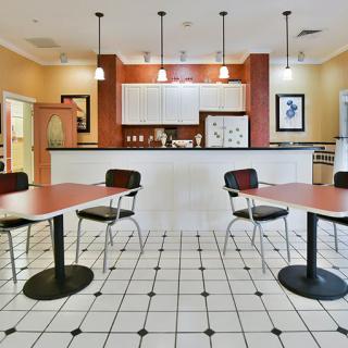 A kitchen and dining area with tables, chairs, and a tiled floor.