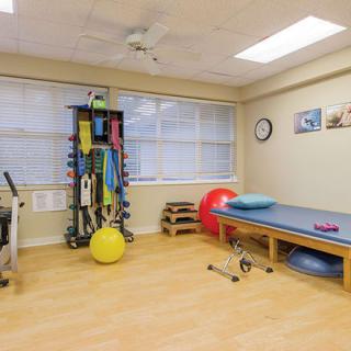A well-equipped physiotherapy room with exercise equipment and a treatment table.
