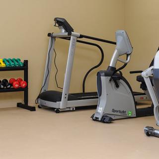 A gym with exercise equipment including a treadmill, stationary bike, and dumbbells.