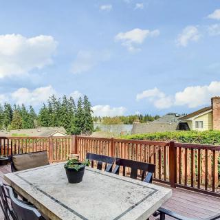 A spacious outdoor deck with a table and chairs, surrounded by trees under a clear blue sky.