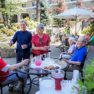A group of seniors enjoying a sunny day and socializing in a garden area.