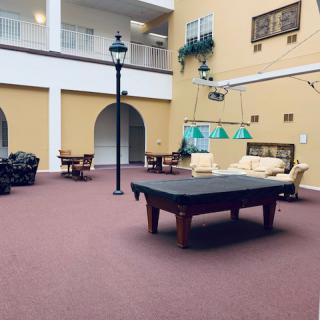 A cozy indoor lounge area featuring a pool table and comfortable seating set against a backdrop of archways and decorative lamp posts.