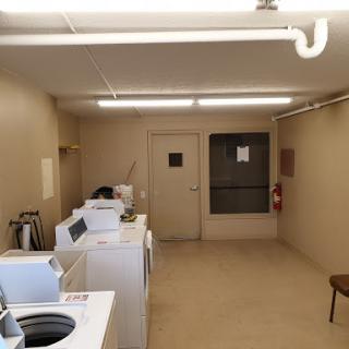 A spacious and well-lit laundry room featuring several washing machines and dryers.