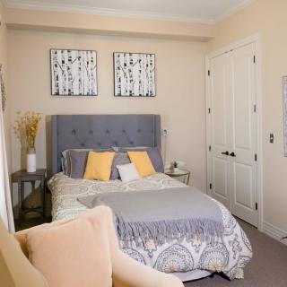 A modern bedroom with elegant decor, featuring a bed with colorful pillows and wall art.