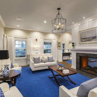 A modern living room featuring white furniture, a blue carpet, and a cozy fireplace.