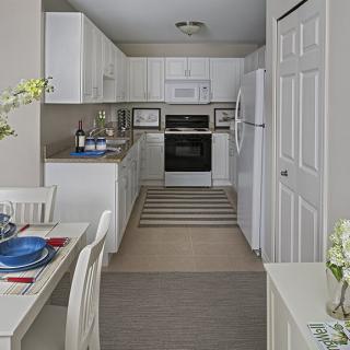 A modern and cozy kitchen with white cabinets and a small dining area.