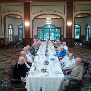 A group of people dining at a long table in a formal setting.
