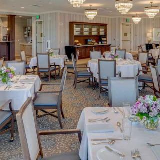 An elegant restaurant dining room with set tables and chandeliers.