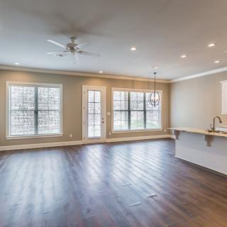 A spacious and modern living room featuring large windows and hardwood flooring.