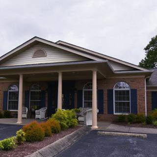 A building with a prominent entrance featuring columns and landscaped surroundings.