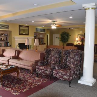 A cozy living room with sofas, armchairs, and a coffee table arranged around a rug.