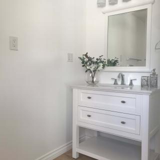 A minimalist bathroom with a white vanity and mirror.