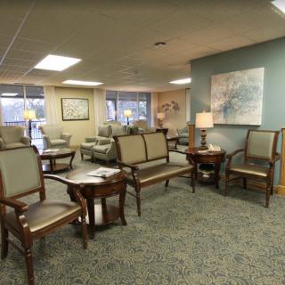A cozy waiting room with chairs, tables, and lamps.
