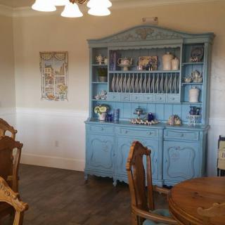 A dining room featuring a vintage blue cabinet and wooden furniture.