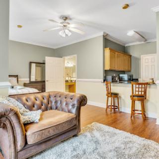 A cozy living room featuring a comfortable sofa, kitchenette, and stylish bar stools.