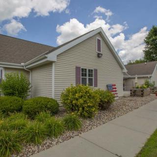 A suburban house with a well-maintained garden and a concrete pathway under a partly cloudy sky.